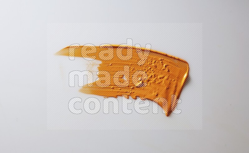 An orange single curved painting knife stroke on white background