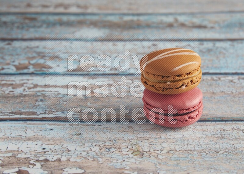 45º Shot of of two assorted Brown Irish Cream, and Pink Raspberry macarons on light blue background