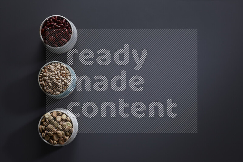 Legumes in pottery bowls on grey background