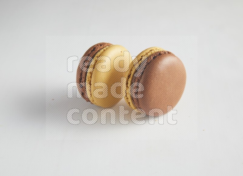 45º Shot of two Yellow and Brown Chai Latte macarons on white background
