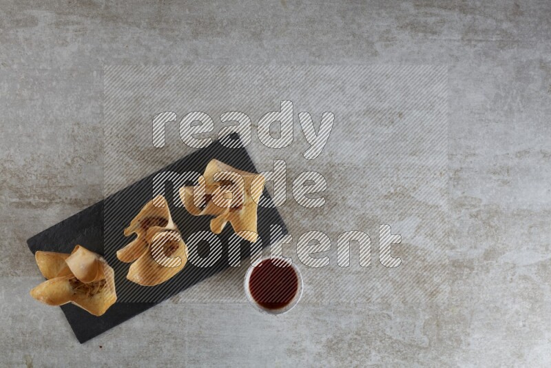 wonton cups with soy sauce ramkin on rectangle slate on grey textured counter top