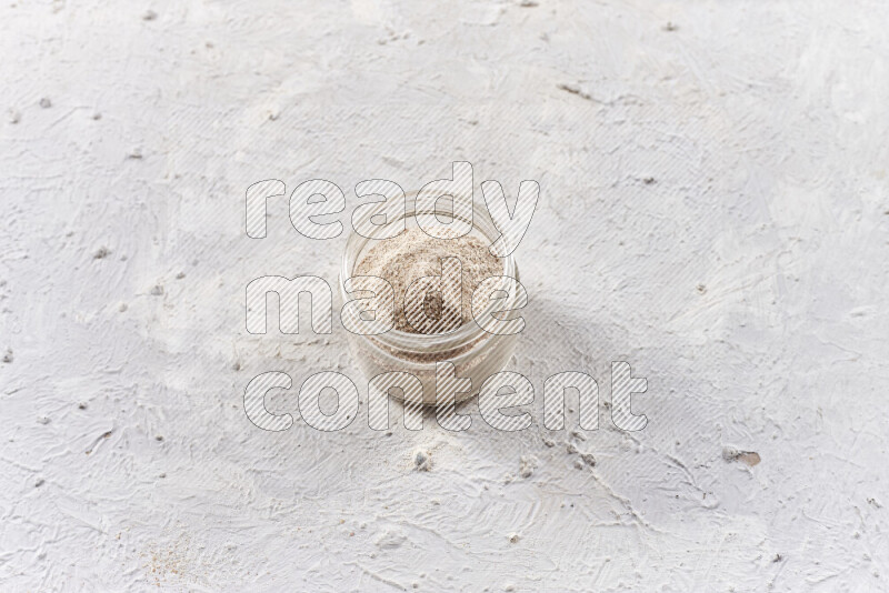 A glass jar full of onion powder on white background