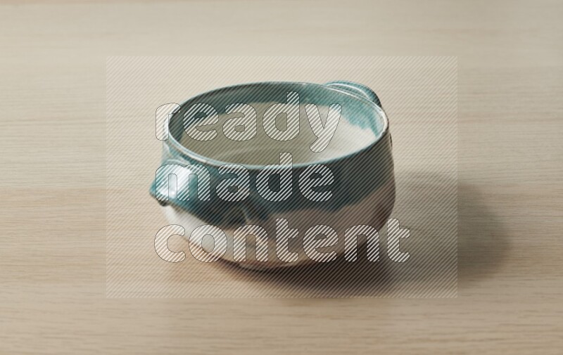 A multicolored pottery bowl on light wooden background