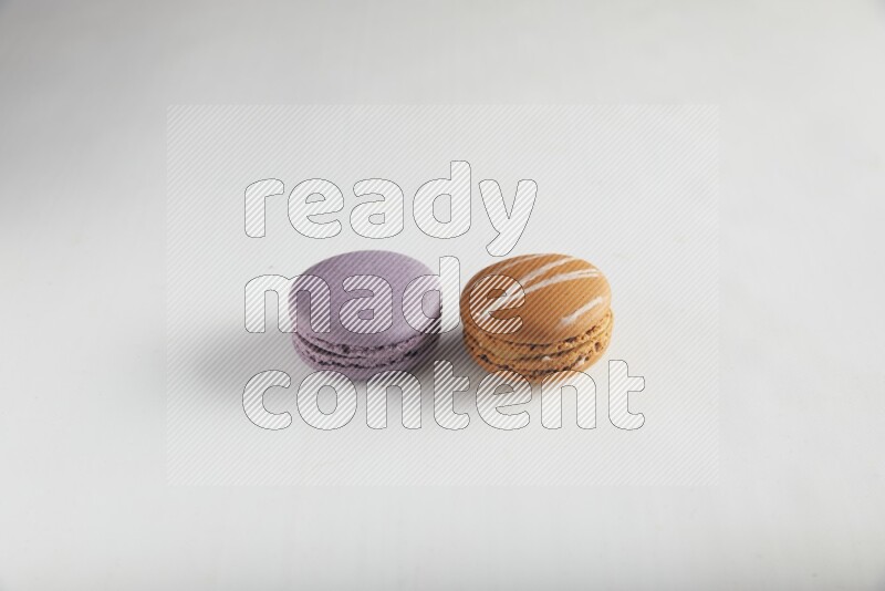 45º Shot of of two assorted Brown Irish Cream, and Purple Blueberry macarons on white background