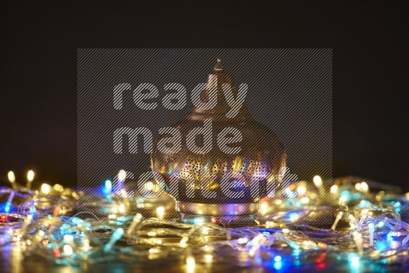 A traditional ramadan lantern surrounded by glowing fairy lights in a dark setup