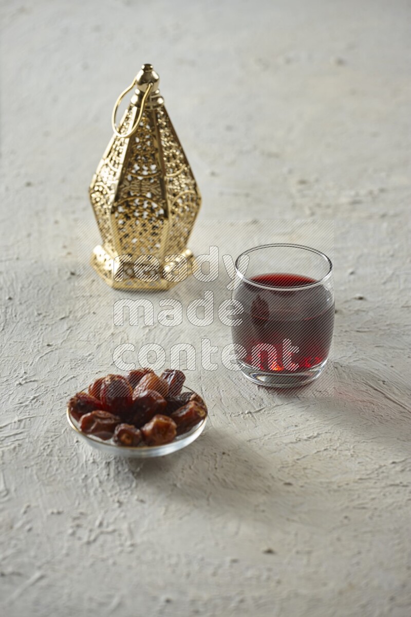 A golden lantern with different drinks, dates, nuts, prayer beads and quran on textured white background