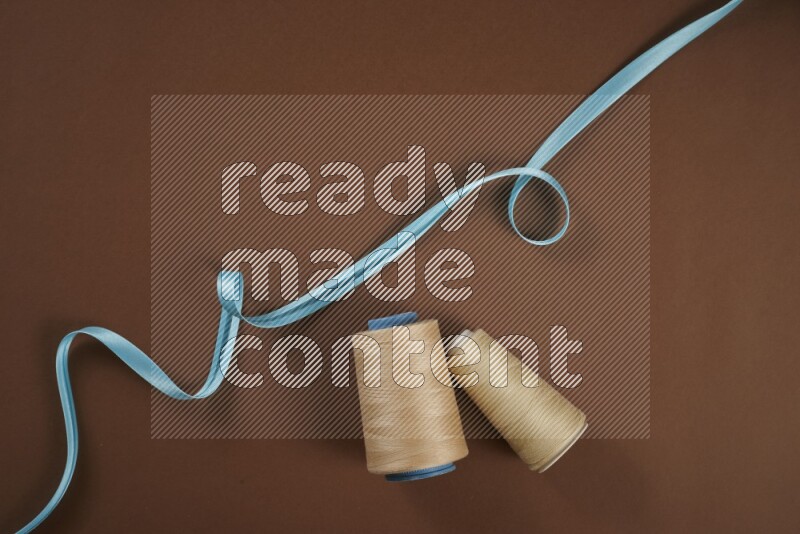 A blue collection of sewing and tailoring tools arranged on a brown background