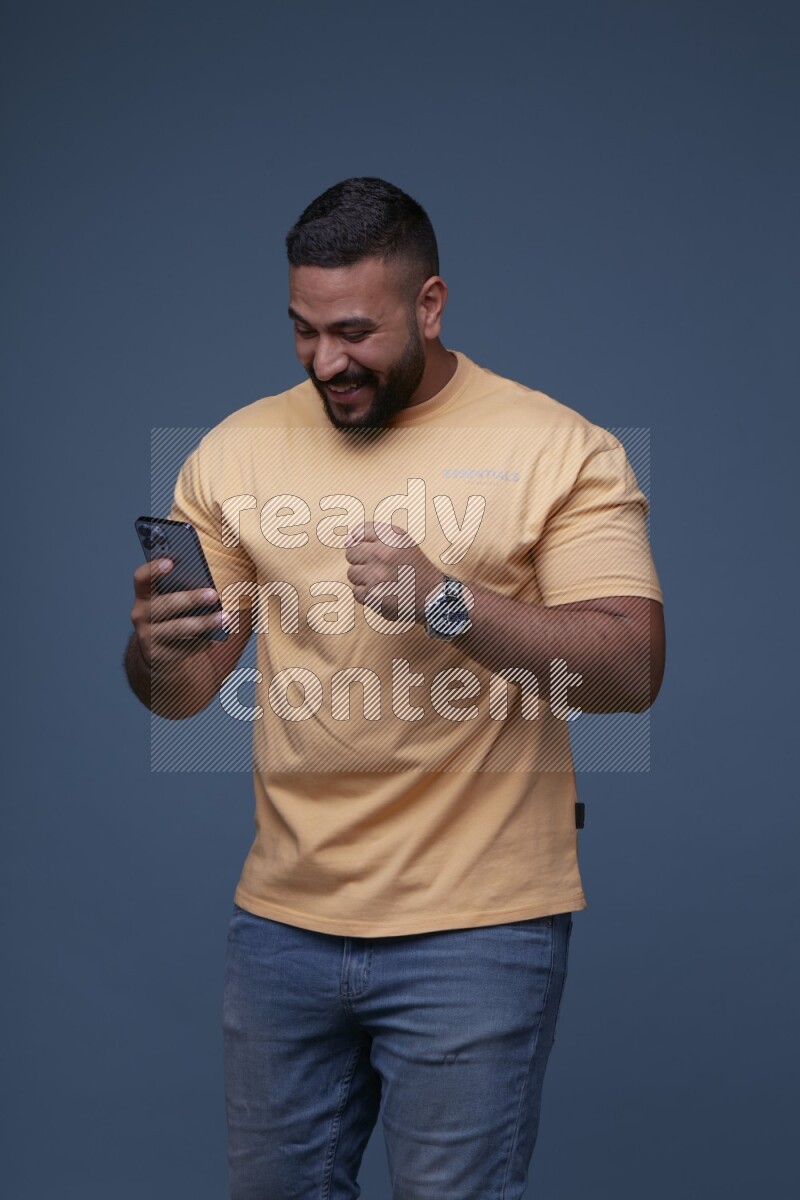 A man Texting on his phone in Blue Background wearing Orange T-shirt