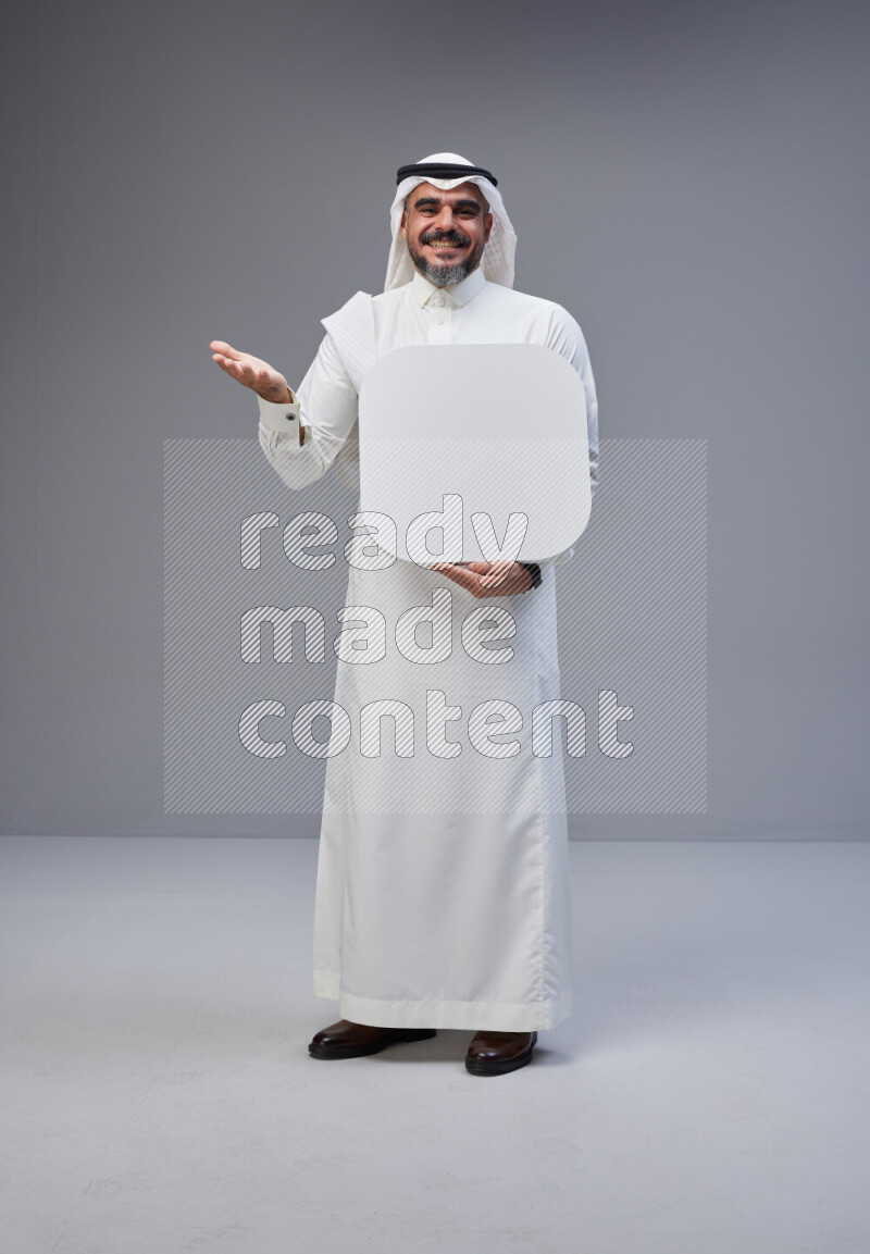 Saudi man Wearing Thob and white Shomag standing holding social media sign on Gray background