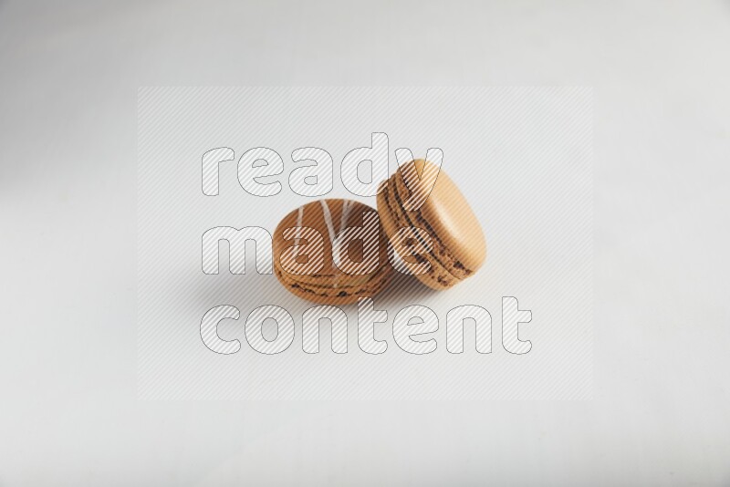45º Shot of of two assorted Brown Irish Cream, and Brown Maple Taffy macarons  on white background