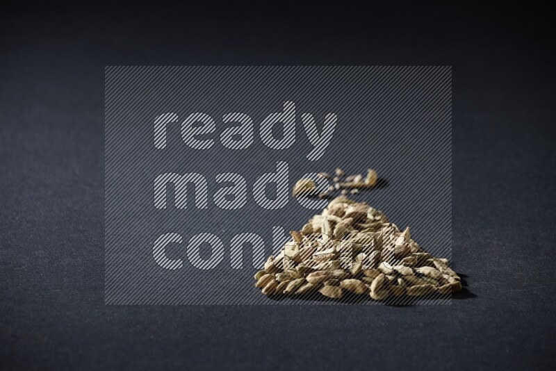 Cardamom in a triangle shape on black flooring