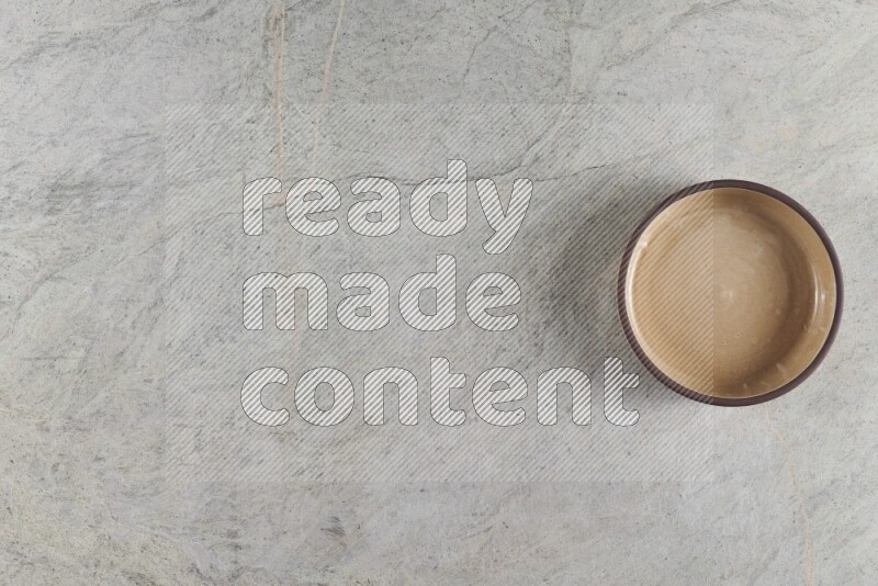 A beige pottery oven bowl on grey marble background