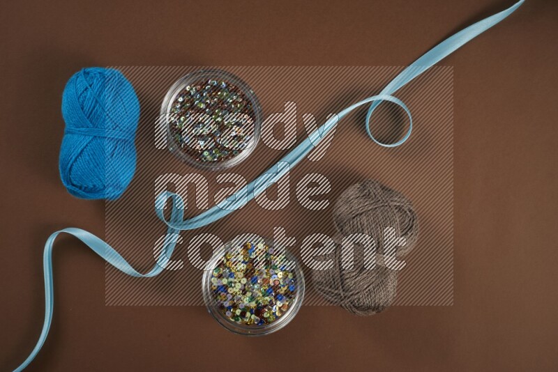 A blue collection of sewing and tailoring tools arranged on a brown background