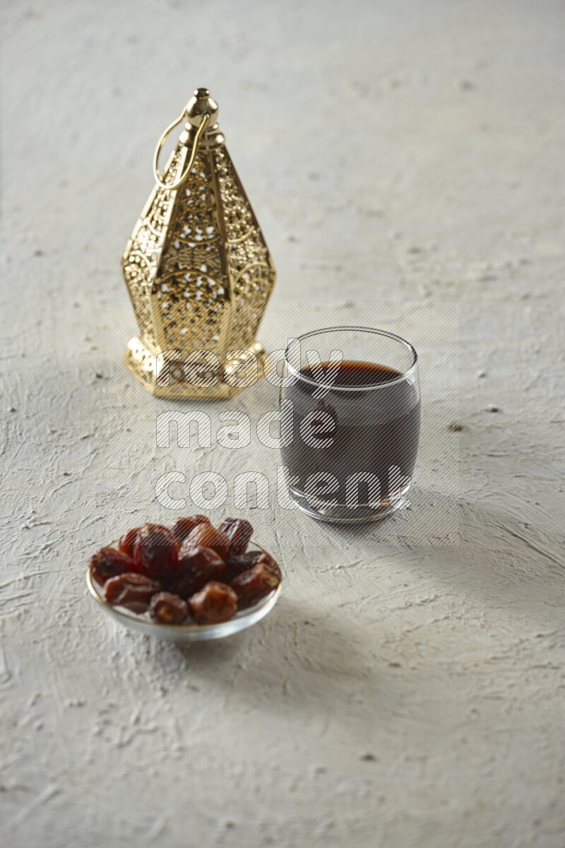 A golden lantern with different drinks, dates, nuts, prayer beads and quran on textured white background