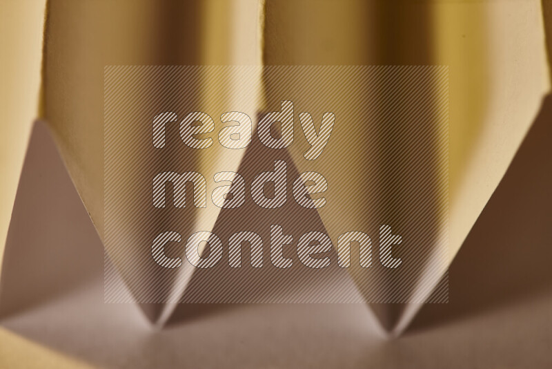 A close-up abstract image showing sharp geometric paper folds in green gradients and warm tones