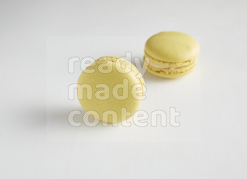 45º Shot of two Yellow Lime macarons on white background