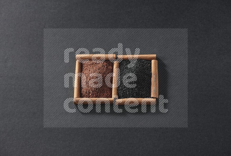 مربعان من أعواد القرفة ممتلئان بحب الرشاد وحبة البركة السوداء علي خلفية سوداء