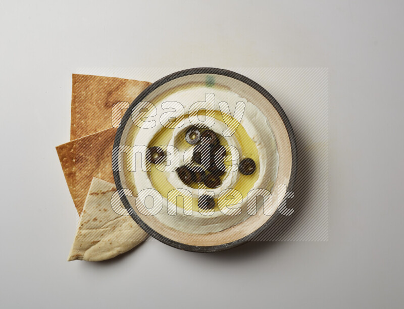 Lebnah garnished with sliced olives in a pottery plate on a white background