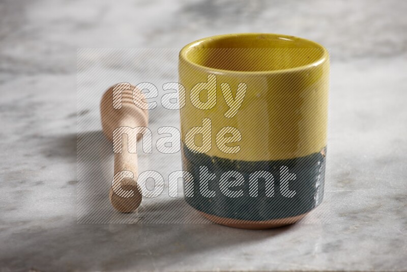 Multicolored pottery cup with wooden honey dipper on the side on grey marble background