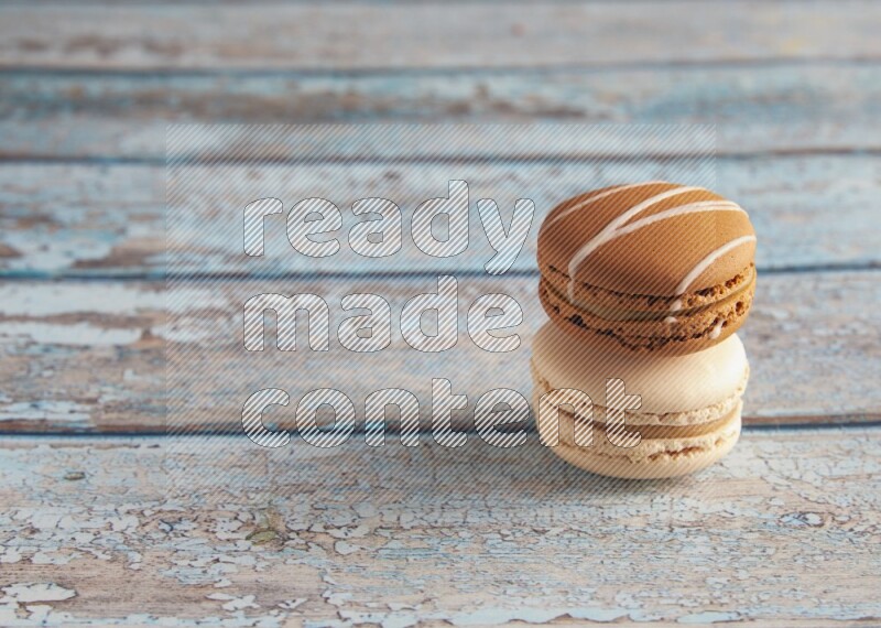 45º Shot of of two assorted Brown Irish Cream, and White Caramel fleur de sel macarons on light blue background