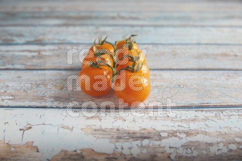 orange cherry tomato vein on a textured blue wooden background 45 degree