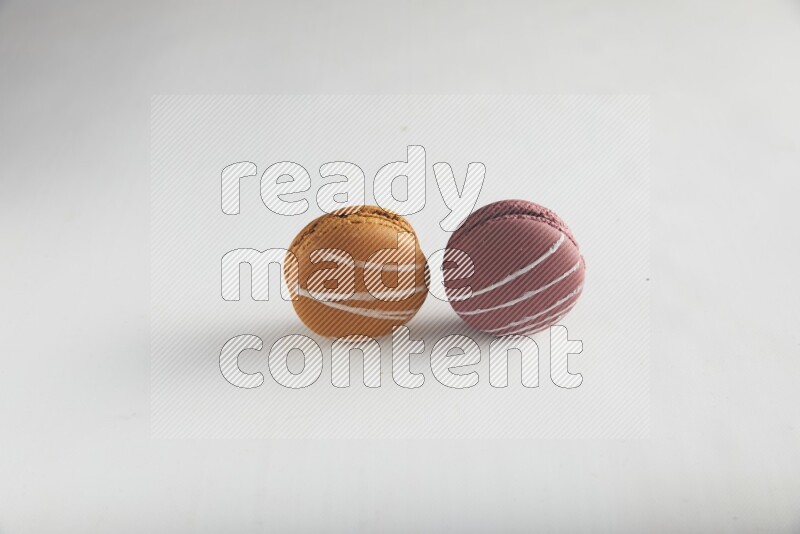 45º Shot of of two assorted Brown Irish Cream, and Red Poppy Flower macarons on white background