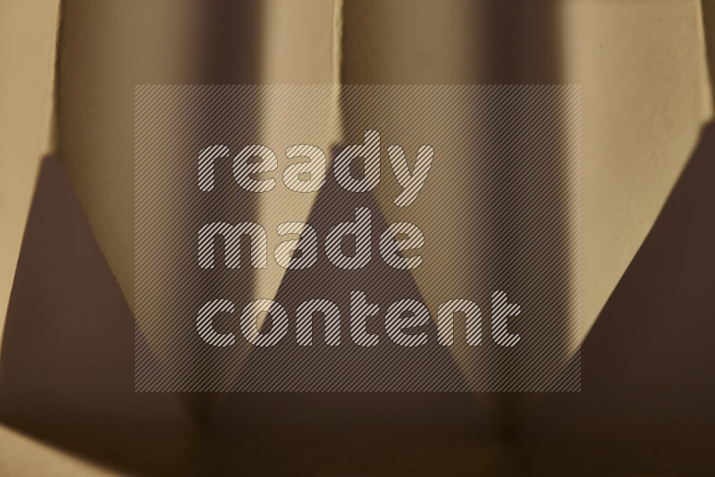 صورة مجردة مقربة تظهر طيات ورقية هندسية حادة بتدرجات الوان دافئة