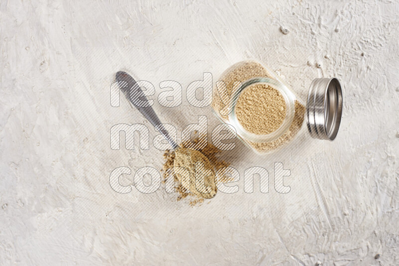 A glass jar full of ground ginger powder on white background