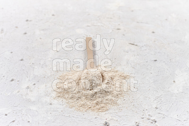 ملعقة خشبية ممتلئة ببودرة البصل علي خلفية بيضاء