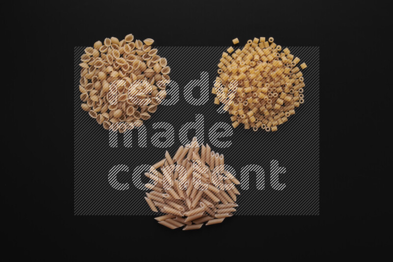 Different pasta types in bunches on black background