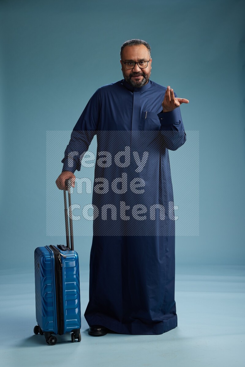 Saudi Man without shimag Standing pulling travel bag on blue background