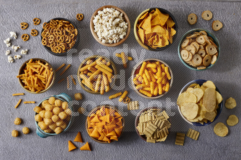 Assorted snacks in pottery bowls on grey background
