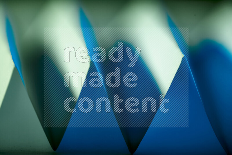 صورة مجردة مقربة تظهر طيات ورقية هندسية حادة بتدرجات اللون الأخضر والأزرق