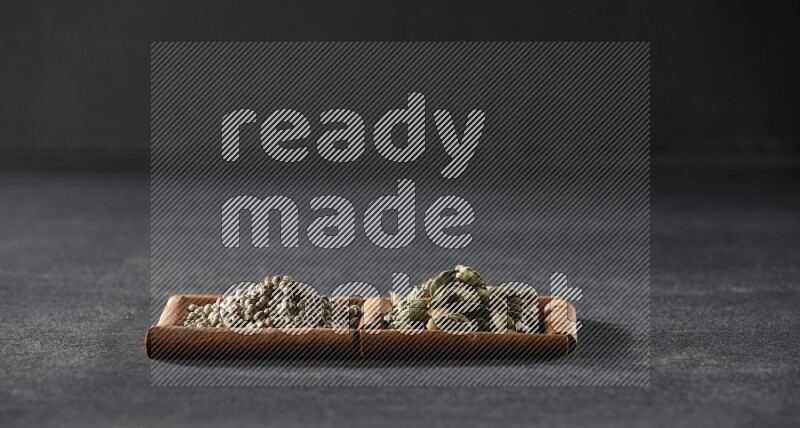 مربعان من أعواد القرفة ممتلئان بحبوب الفلفل الأبيض وحبوب الهيل علي خلفية سوداء