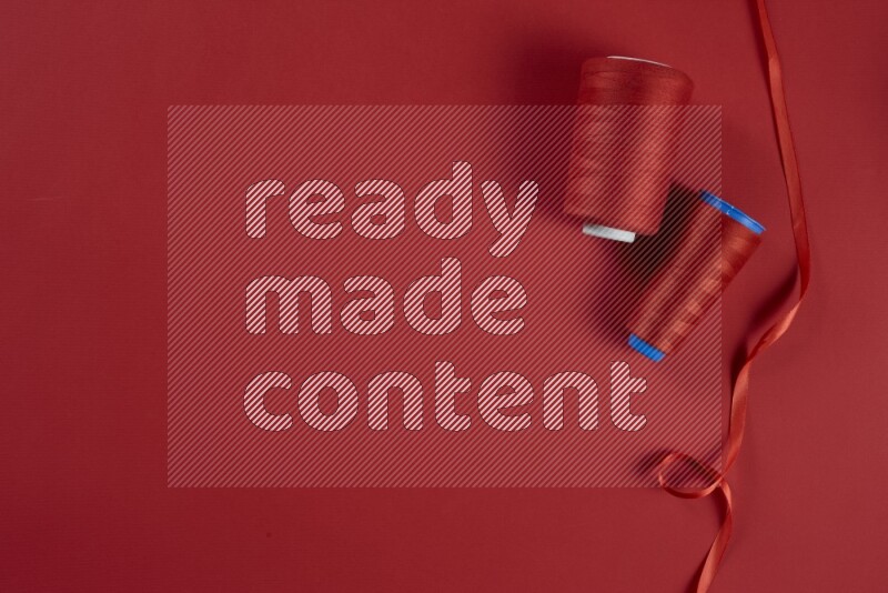 A red collection of sewing and tailoring tools arranged on a red background