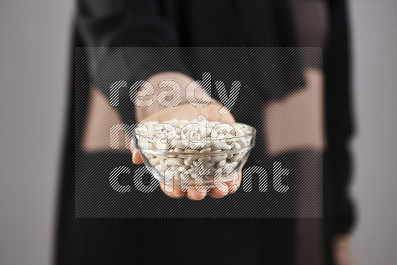 Woman in abaya holding different kinds of legumes in different positions