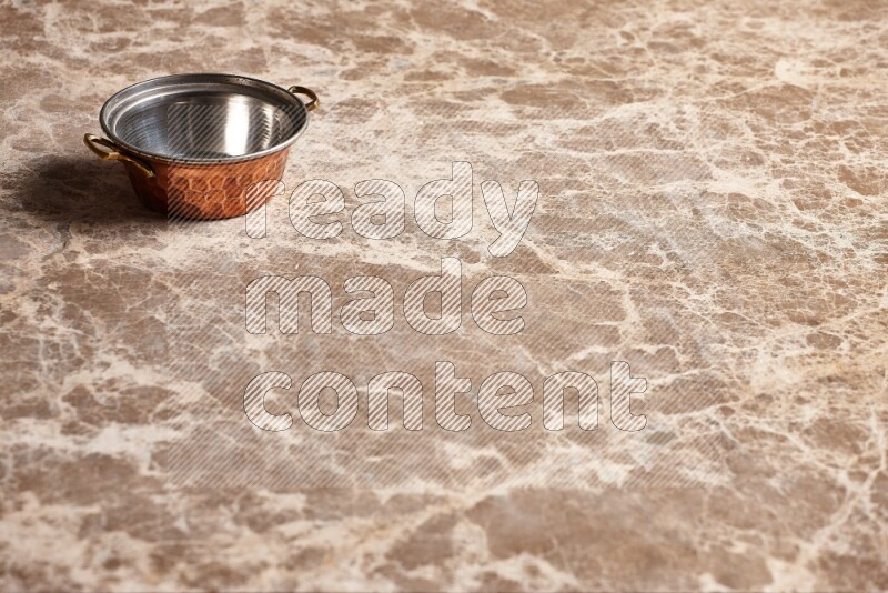 A small copper pot on beige marble background
