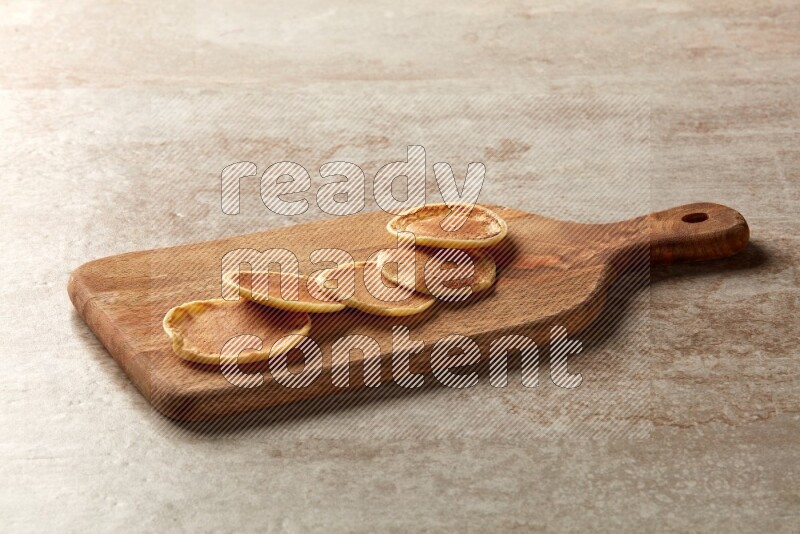 Five stacked plain mini pancakes on a wooden board on beige background