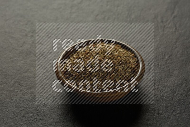 multi color round sauce bowl filled with herbs on grey textured countertop