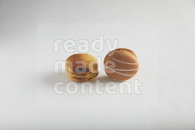 45º Shot of of two assorted Brown Irish Cream, and Yellow Crème Brulée macarons on white background