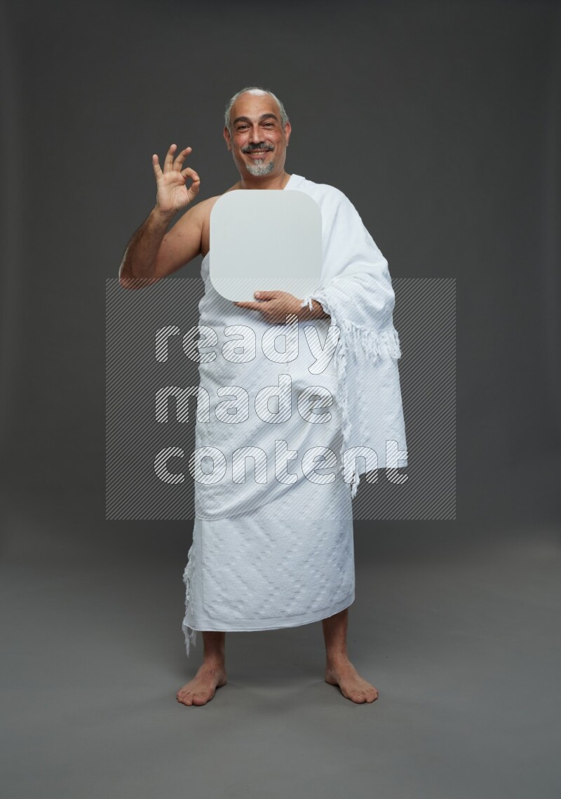 A man wearing Ehram Standing holding social media sign on gray background