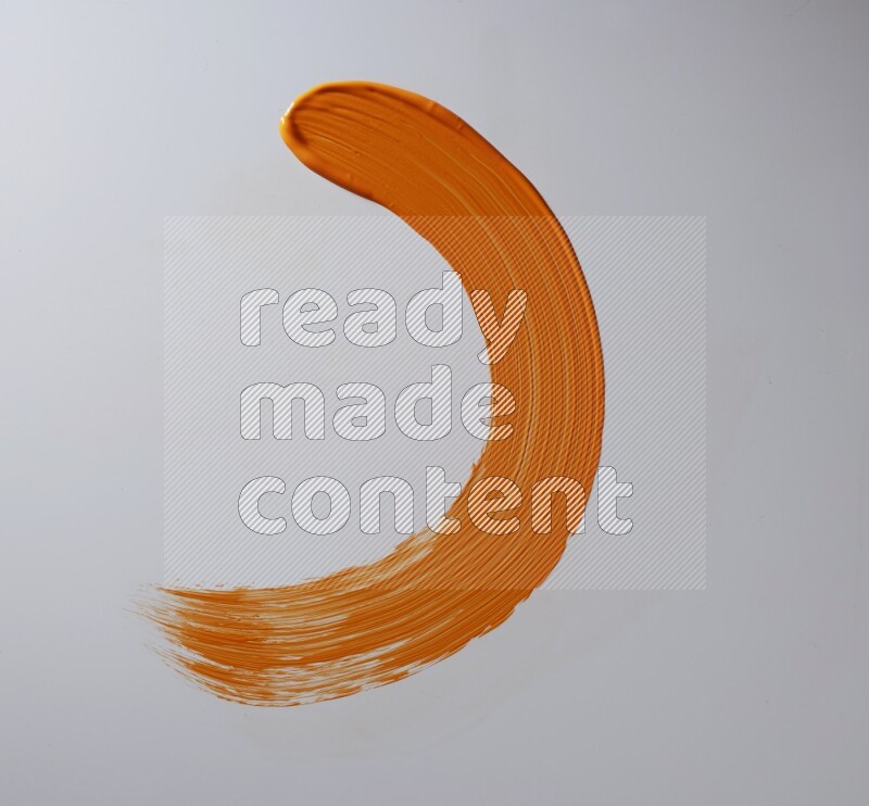 An orange half circular painting brush stroke on white background