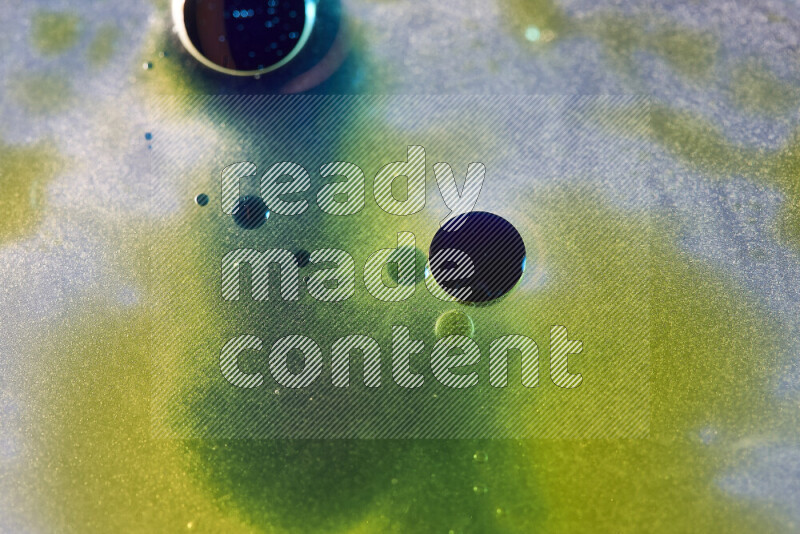 Close-ups of abstract yellow, blue and green watercolor drops on oil Surface on white background