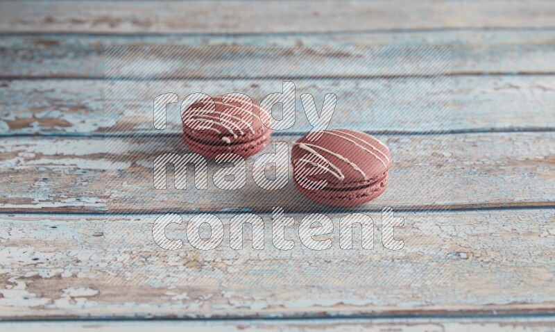 45º Shot of two Red Poppy Flower macarons on light blue wooden background
