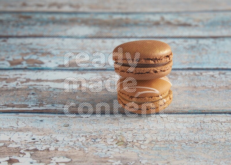45º Shot of of two assorted Brown Irish Cream, and Brown Coffee macarons on light blue background