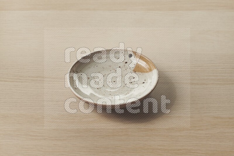 A multicolored pottery plate on light wooden background