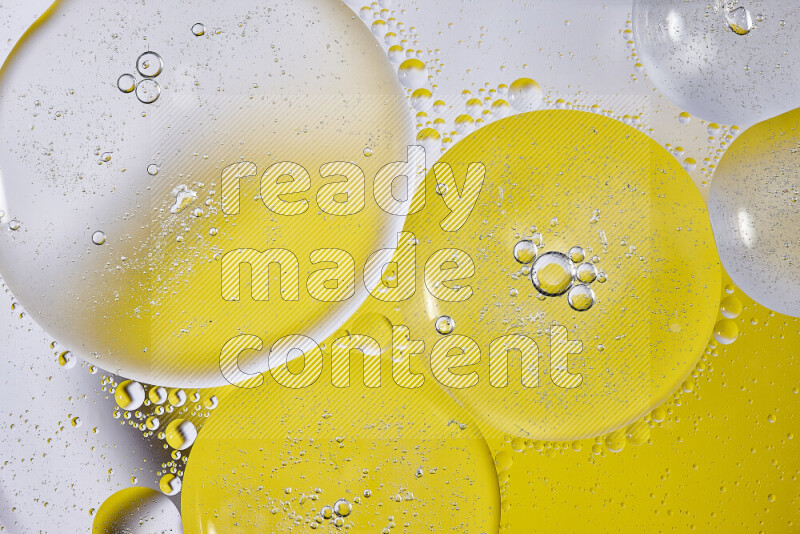 Close-ups of abstract oil bubbles on water surface in shades of white and yellow