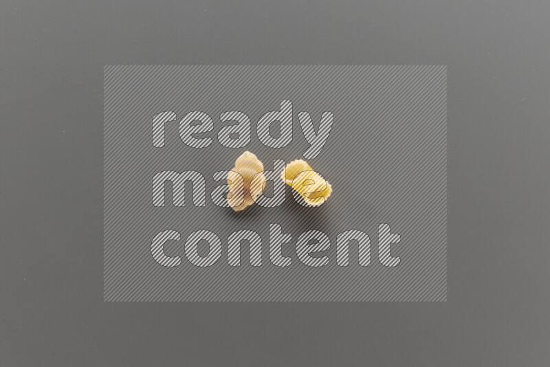 Snails pasta with other types of pasta on grey background