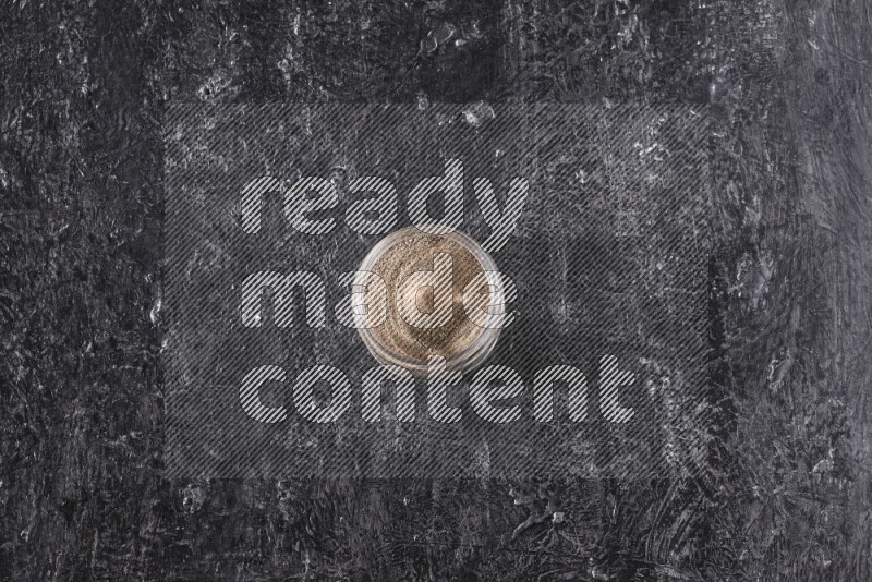 بودرة الفلفل الأسود في وعاء زجاجي علي خلفية سوداء