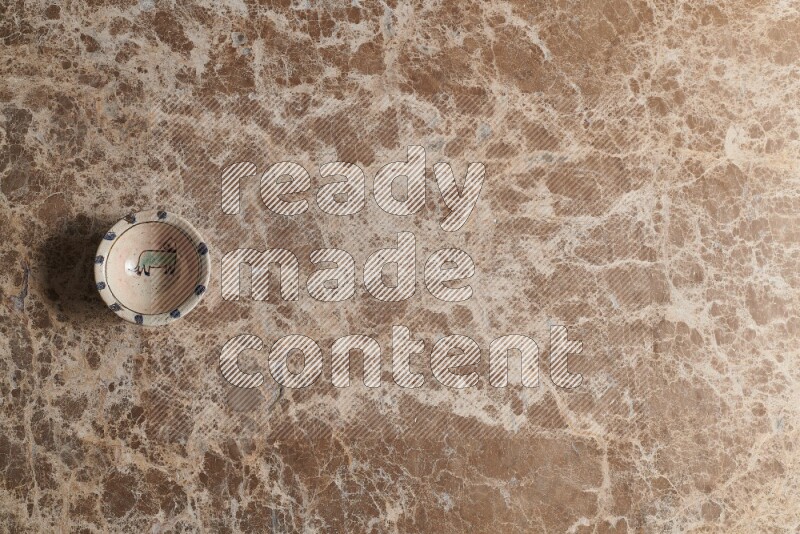 A multicolored pottery bowl on beige marble background
